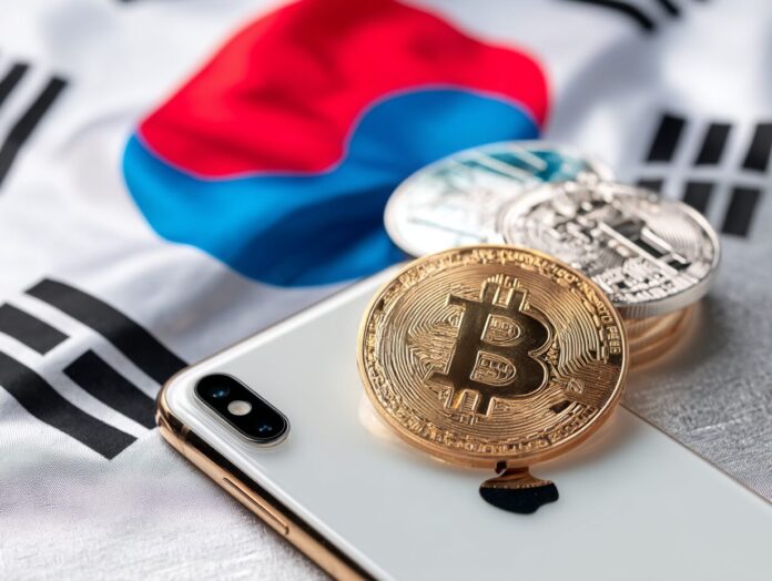 A South Korean flag in the background of a smartphone screen showing crypto app icons being blocked or removed.