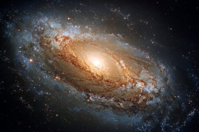 A spiral galaxy with two sweeping arms and a luminous, energetic core glowing at its center.