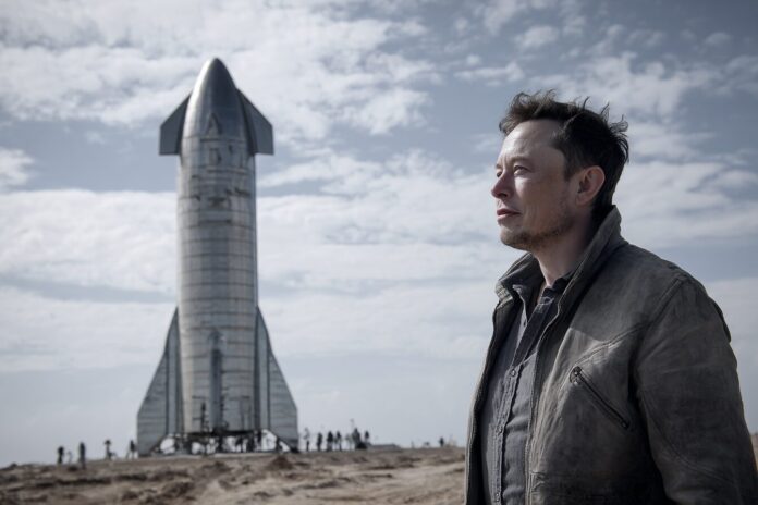 Elon Musk standing before a SpaceX Starship rocket at launch site
