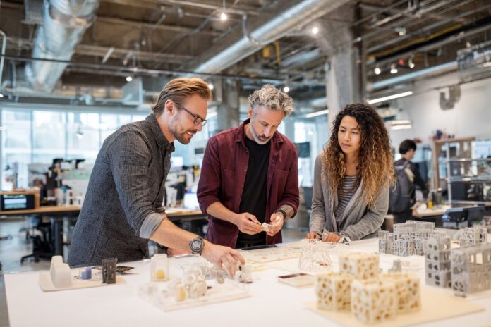 Prototyping team collaborating in a modern lab, reviewing a 3D printed model.