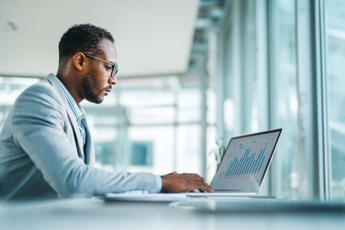 Professional looking businessperson working with data on a laptop in a bright office
