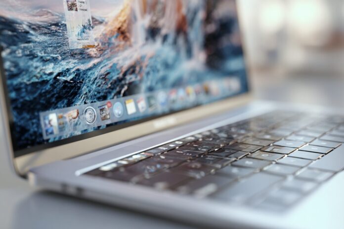 Close-up of MacBook Pro displaying macOS Tahoe with Liquid Glass UI