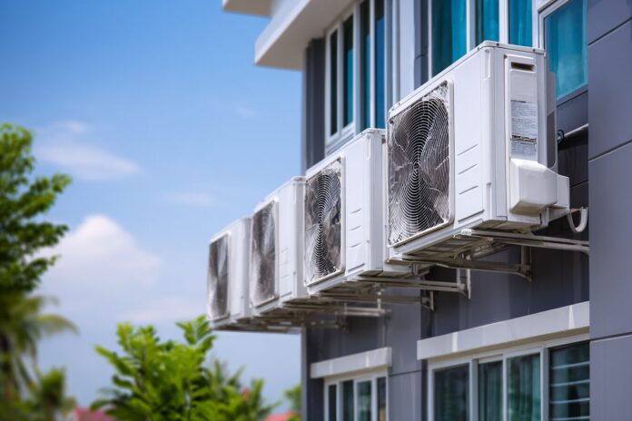 Row of energy efficient air conditioners installed outside smart homes, under a blue sky