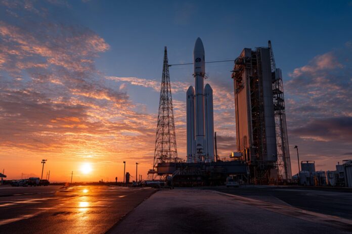 H-2A rocket ready on the launch pad with GOSAT-GW payload, sun rising in the background.