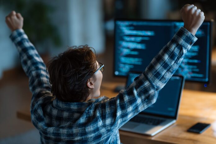 A person using an AI-powered coding assistant on their laptop, looking excited about their app launch.