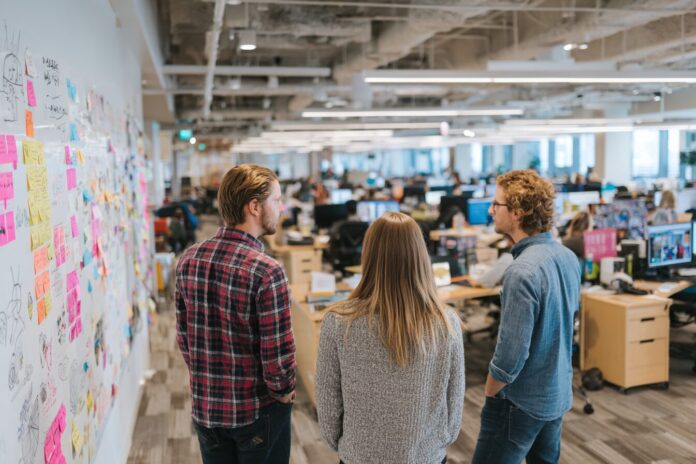 A close-knit engineering team collaborating in a modern open office, whiteboards and sketches emphasizing shared goals and autonomy.