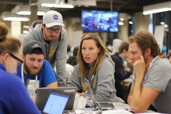 Team members collaborating at the NASA Space Apps Challenge hackathon, gathered around laptops and brainstorming ideas.