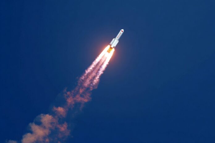 A Chinese rocket carrying the Tianzhou 9 cargo spacecraft launches into a blue sky, leaving a bright trail behind.
