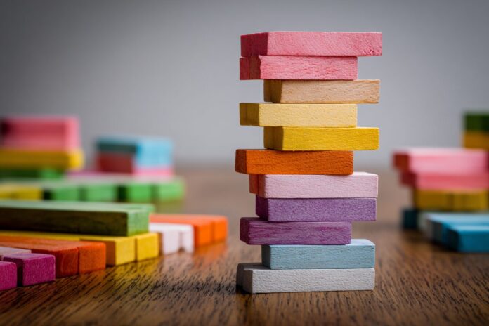 A precarious stack of identical blocks extending far beyond a table edge, illustrating the block-stacking problem.