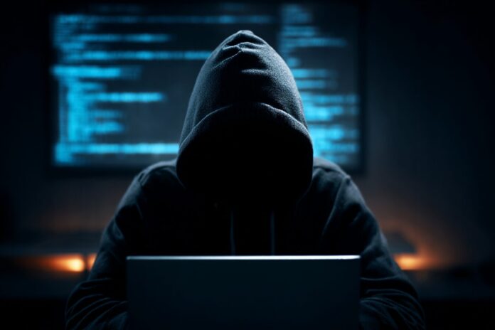 A shadowy figure in a hoodie sits at a computer, code reflecting on their face, symbolizing the anonymous hacker.