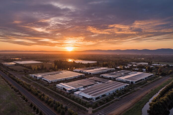 Aerial view of a modern solar-powered data center complex at sunset, symbolizing sustainable AI infrastructure.