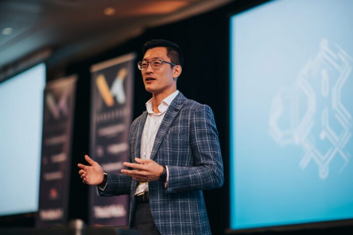 Yat Siu speaking at a blockchain conference, standing in front of a screen displaying Animoca Brands and DigitalX logos.