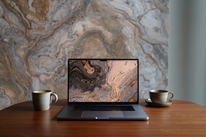 Apple Silicon MacBook Pro on desk with macOS 26 Tahoe wallpaper