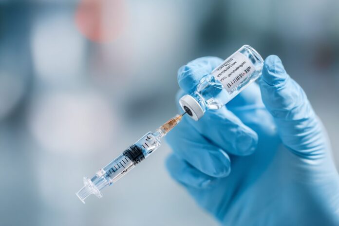 A close-up of a healthcare professional's hand holding a vaccine vial and syringe, symbolizing changes in U.S. vaccine policy.