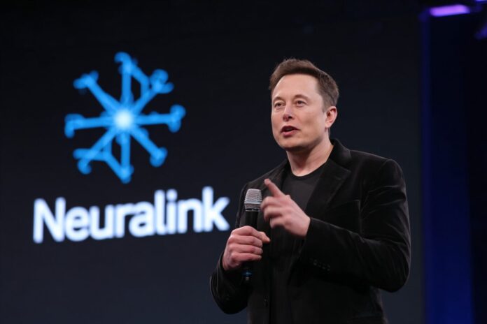 Elon Musk speaks at a Neuralink event while a Neuralink logo displays on a screen.