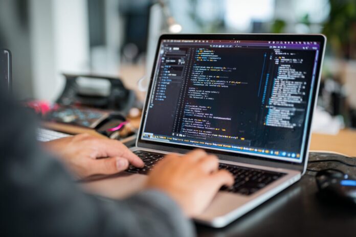 A developer using GitHub Spark on a laptop to describe an app idea in natural language.
