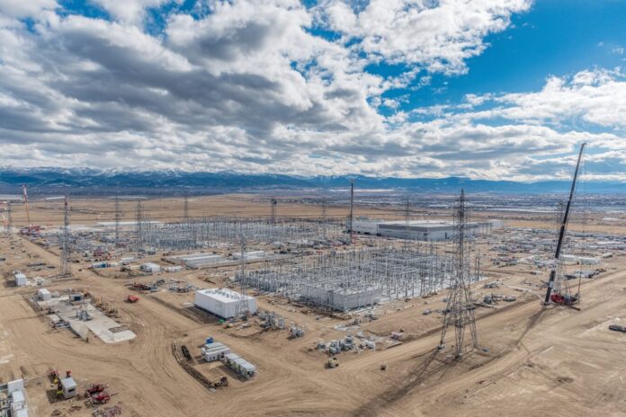 Aerial photograph showing a massive AI data center construction site with cranes, servers, and energy infrastructure.