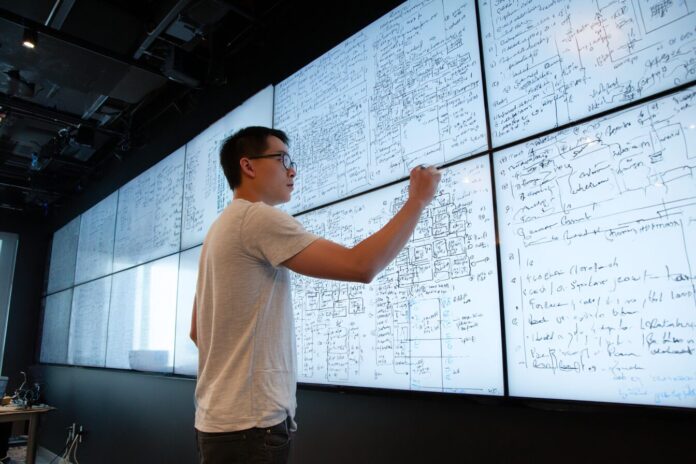 A researcher reviews formal logic statements on a large screen in a cloud computing lab, symbolizing AWS automated reasoning systems.