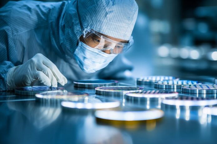 Technician examining silicon wafers in a semiconductor fabrication cleanroom