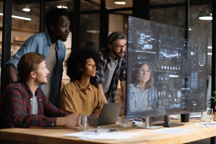 A diverse team reviews AI-powered hiring results together on a large screen in an office setting.