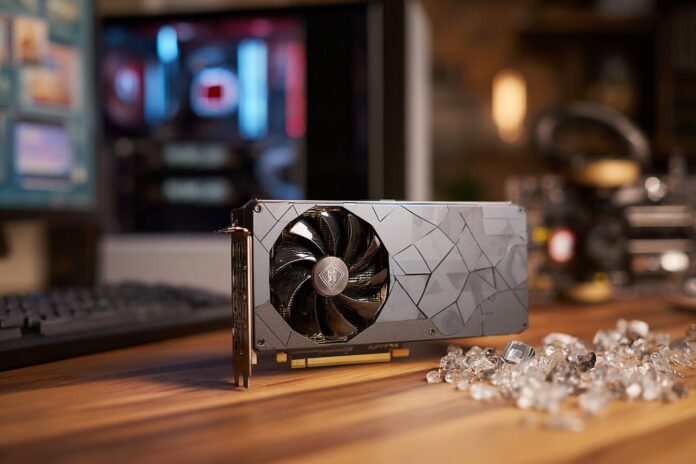 A next-generation AMD discrete NPU card showcased on a wooden desk, with blurred PC components in the background.