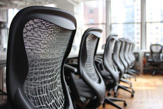 A row of empty office chairs in a technology company workspace symbolizing widespread layoffs.