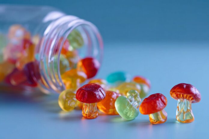 Colorful gummy mushrooms spilled from a packaging on a table