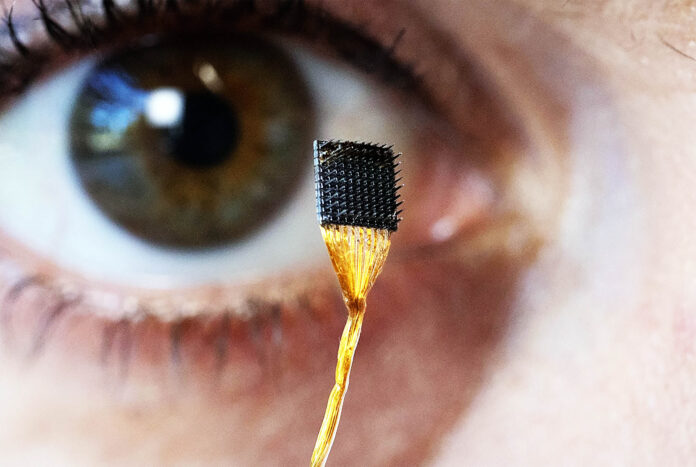 Researcher Erin Kunz holding a microelectrode array used for brain-computer interface studies.