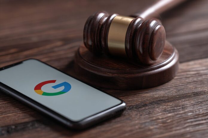 A gavel near a mobile phone showing the Google Play Store logo, symbolizing a court ruling against Google.