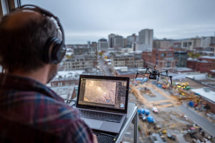 A NASA engineer monitors a drone's flight path on a laptop in a cityscape test environment.
