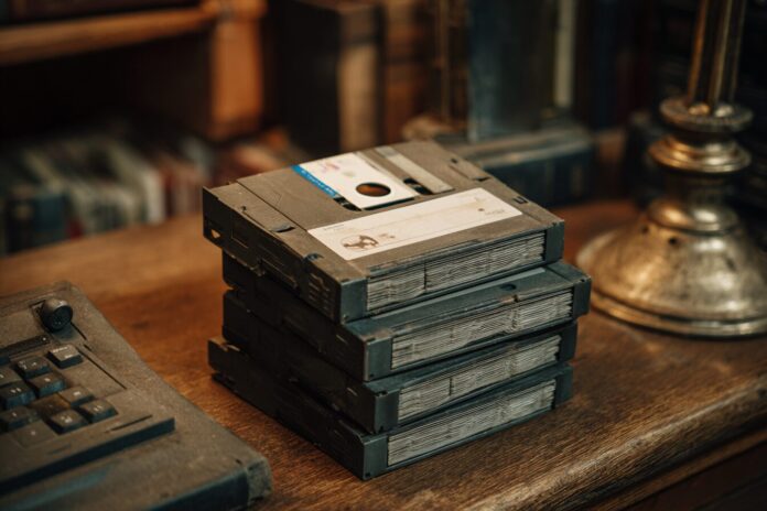 A stack of 3.5-inch floppy disks on an old wooden desk in a prison library