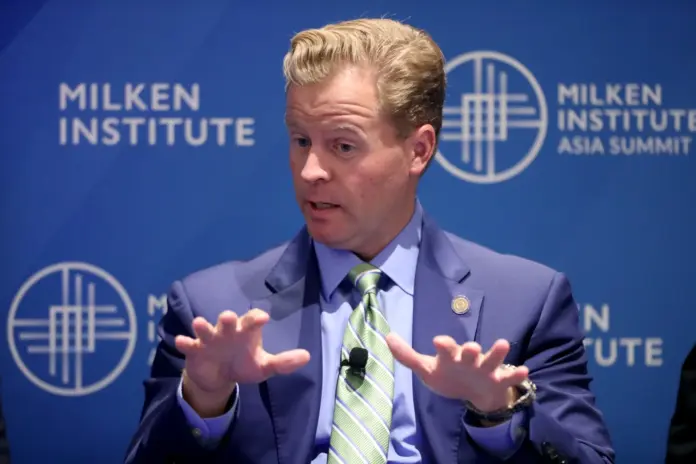 Brian Quintenz speaks at a digital asset conference, gesturing toward regulatory charts.