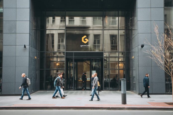 Exterior view of the Gemini cryptocurrency exchange office building with people walking past.