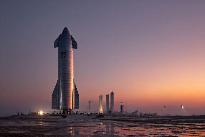 SpaceX Starship launch pad at dusk with the rocket awaiting liftoff.