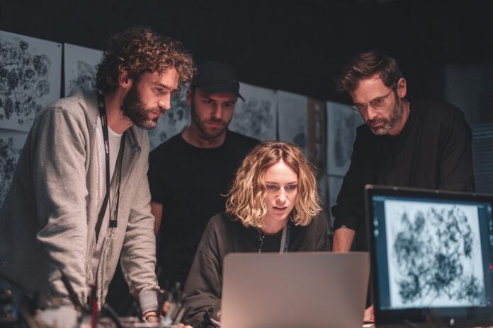 Team of filmmakers collaborating around a laptop with AI-generated sketches displayed.