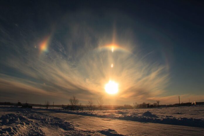Sun dogs as bright, colorful spots beside the sun in a winter sky.