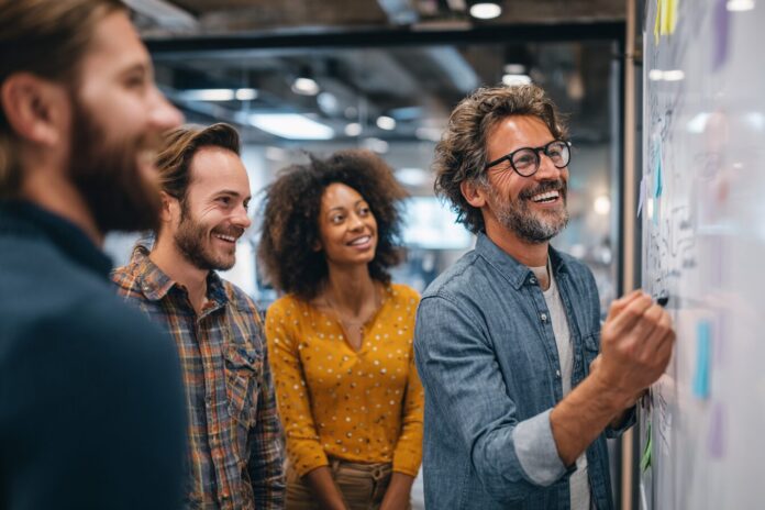 A diverse group of startup founders discussing strategies at a whiteboard in a modern co-working space.