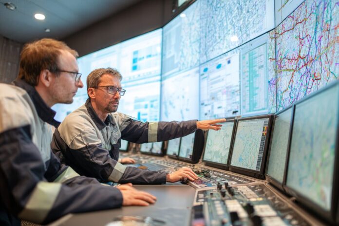 Engineers collaborating with an AI-powered nuclear operations dashboard at a control room.