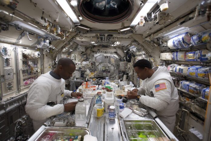 Astronauts conducting a science experiment inside the International Space Station laboratory module.