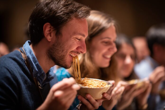 Researchers enjoying a bowl of cacio e pepe pasta at the Ig Nobel ceremony, highlighting the physics behind perfect pasta sauce.