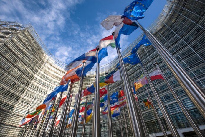 European Union headquarters with flags in front, symbolizing regulatory action