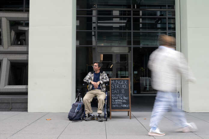 Guido Reichstadter sits outside Anthropic headquarters with a protest sign, San Francisco
