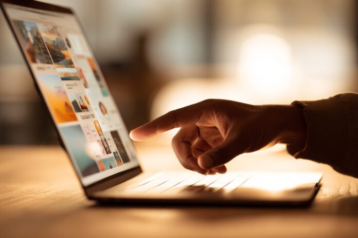 Close-up of a hand interacting with a MacBook screen with a touch-friendly interface.