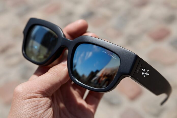Meta Ray-Ban Display smartglasses held in hand, showing lens display.
