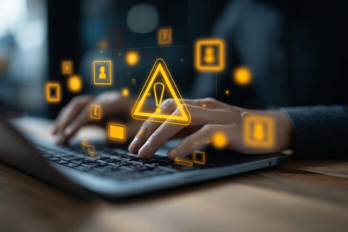 Person typing on a laptop with warning cybersecurity icons overlaid
