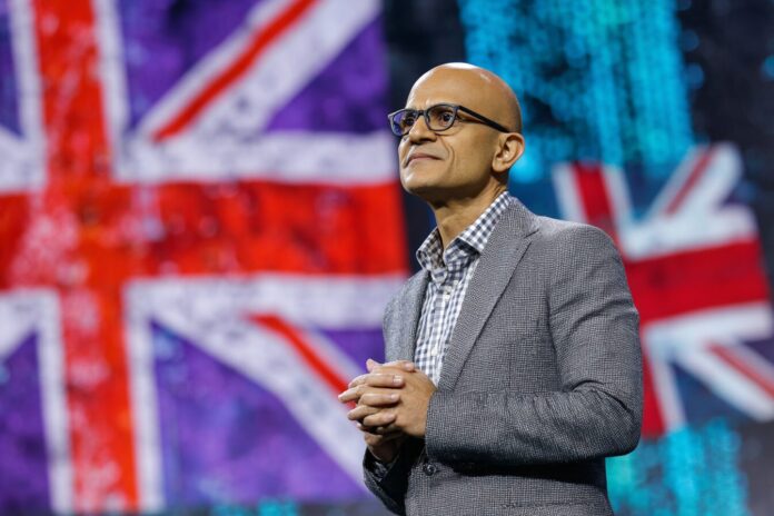 Microsoft CEO Satya Nadella announces UK investment at major tech conference, standing in front of Microsoft and UK flags.