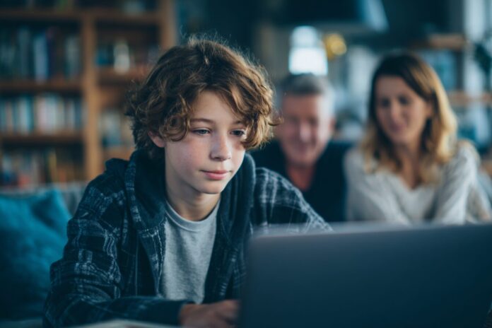 Teen using laptop while parents monitor screen