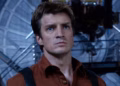Nathan Fillion standing before the Serenity spaceship in a dramatic sci-fi setting with atmospheric lighting and space debris floating around